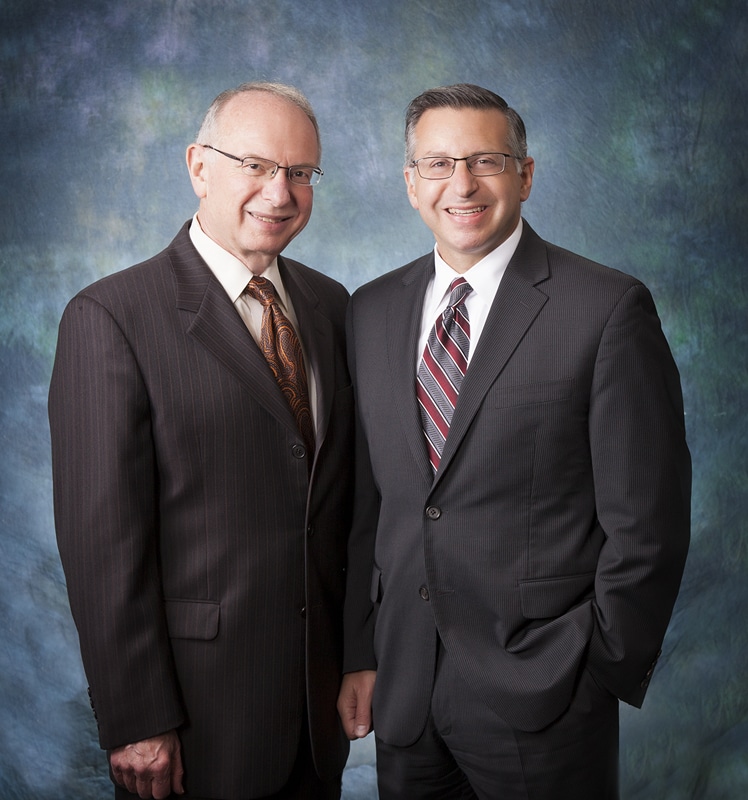 Two business partners photographed together on a painted backdrop