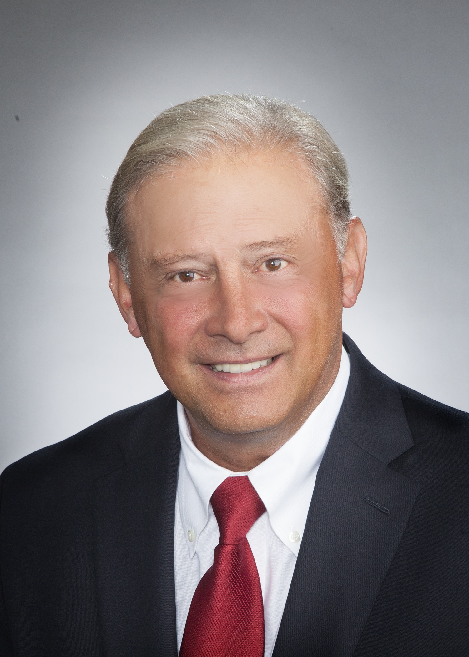Corporate headshot on a soft gray backdrop from a matched company team set