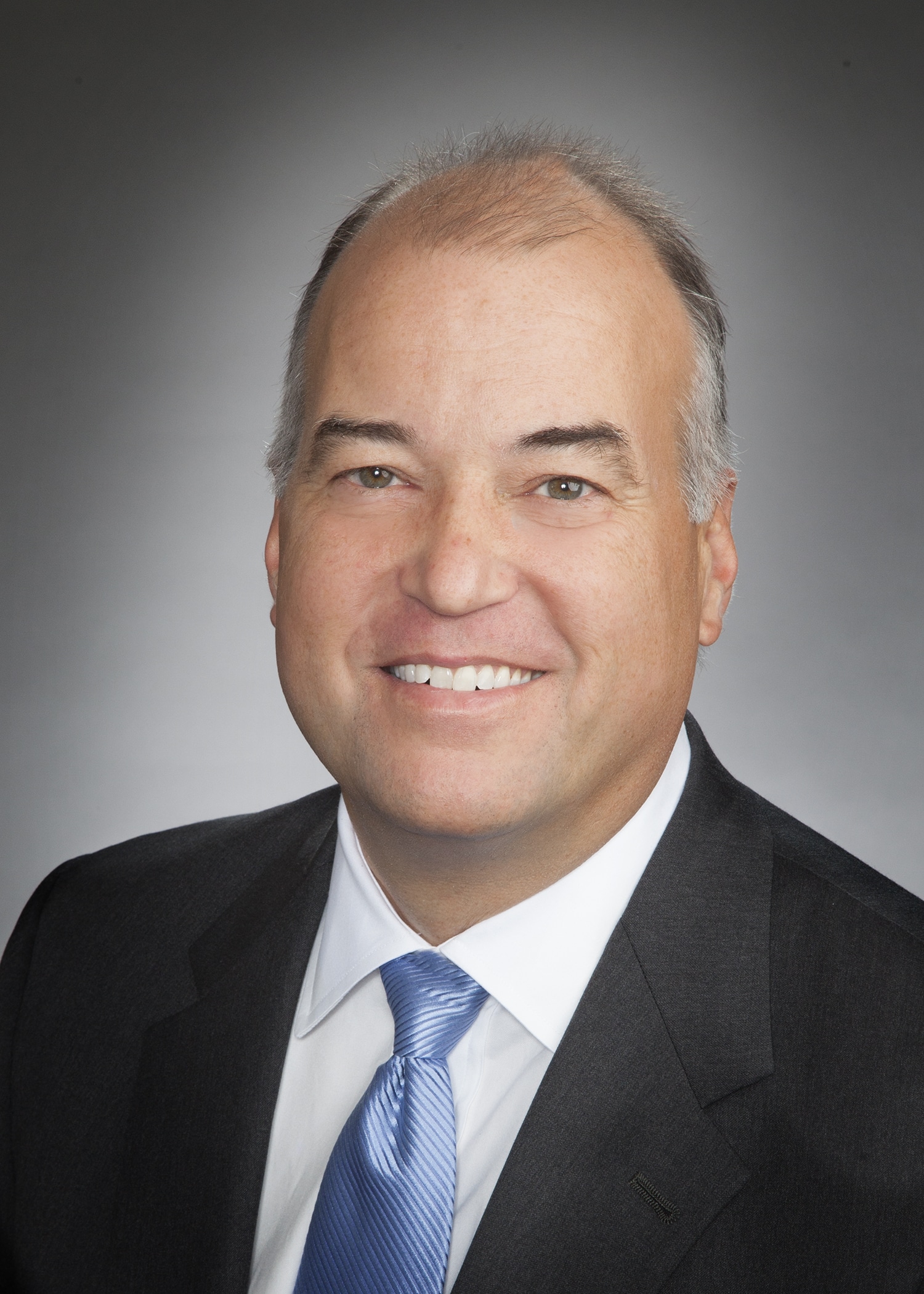 Corporate headshot on a soft gray backdrop from a matched company team set