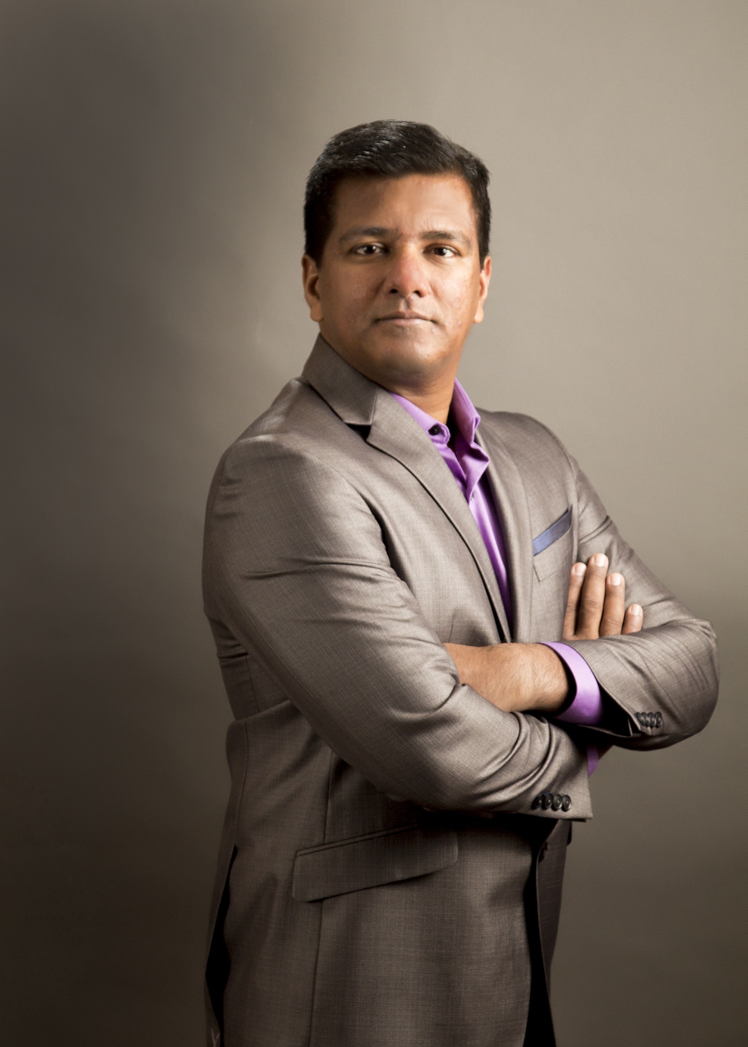 Executive portrait with arms crossed on a warm backdrop