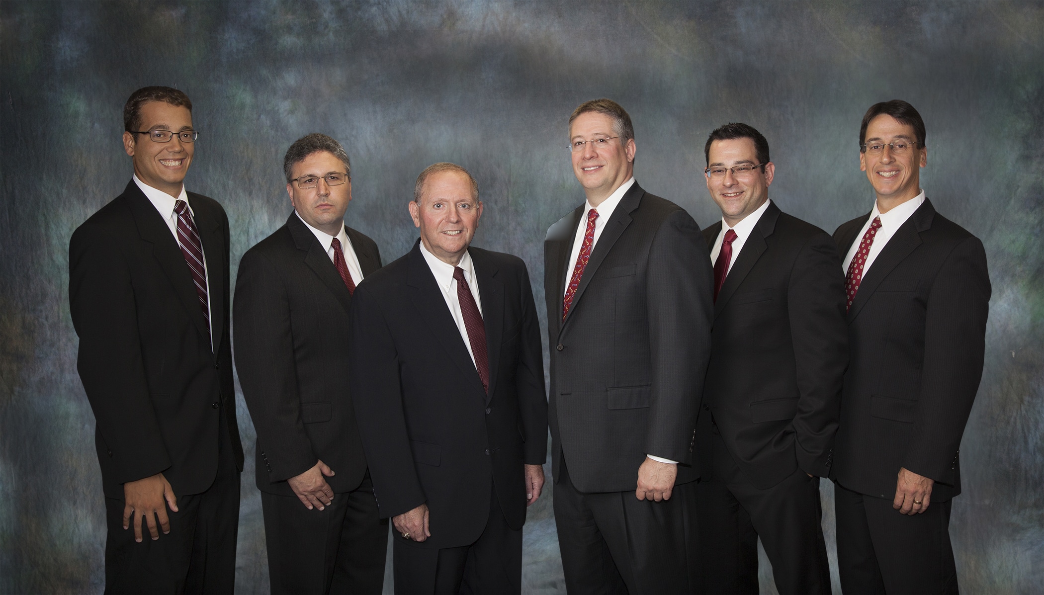 Law firm partners group portrait on a blue backdrop
