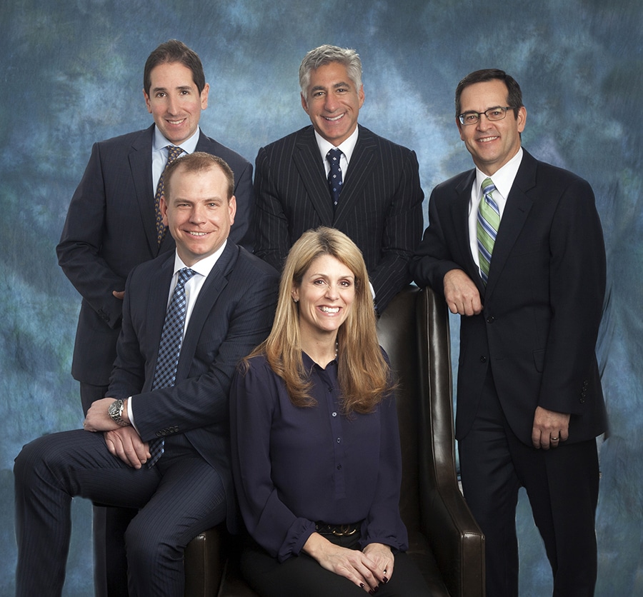 Executive team portrait with five partners on a blue backdrop
