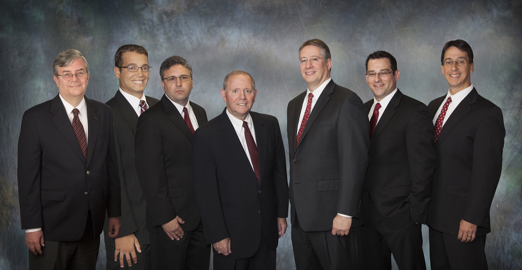 Law firm partners group portrait on a blue backdrop