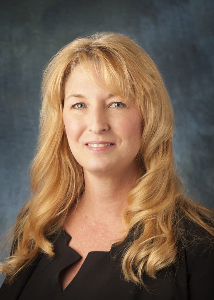 Staff headshot on a blue-gray backdrop for a company website and directory