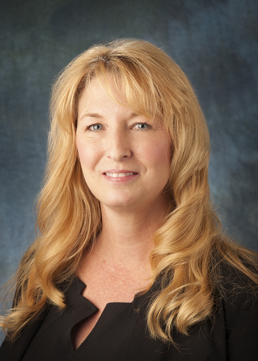 Staff headshot on a blue-gray backdrop for a company website and directory