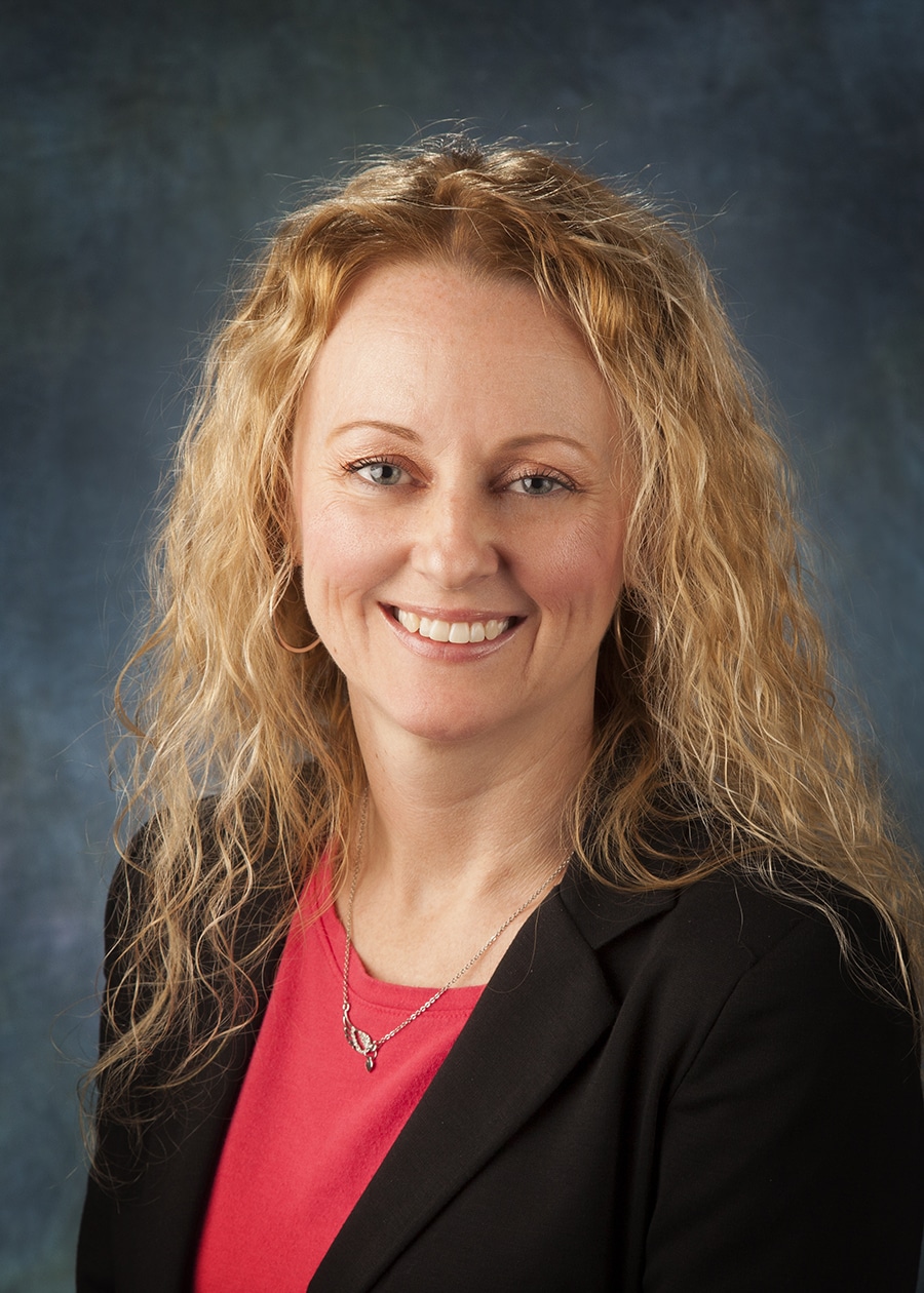 Staff headshot on a blue-gray backdrop for a company website and directory