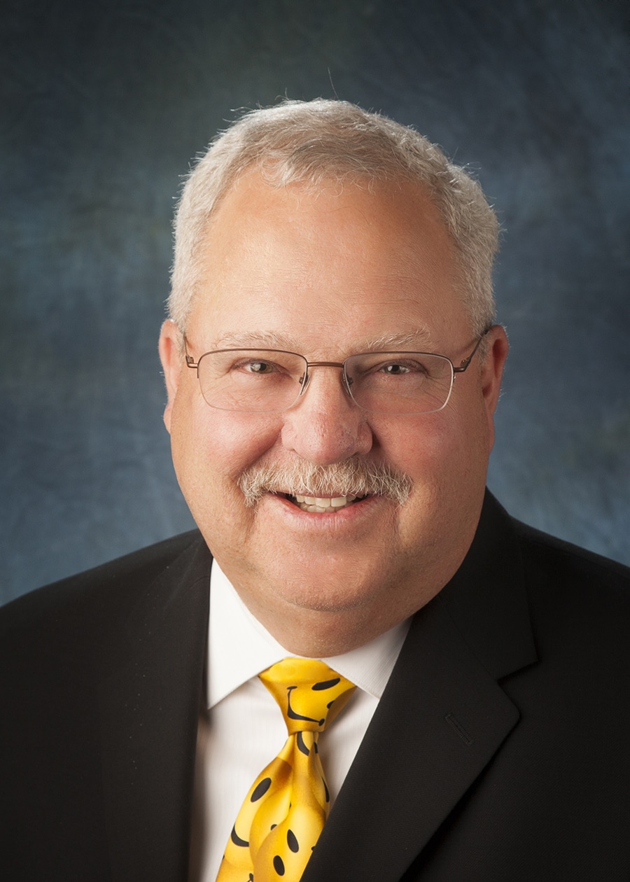 Staff headshot on a blue-gray backdrop for a company website and directory