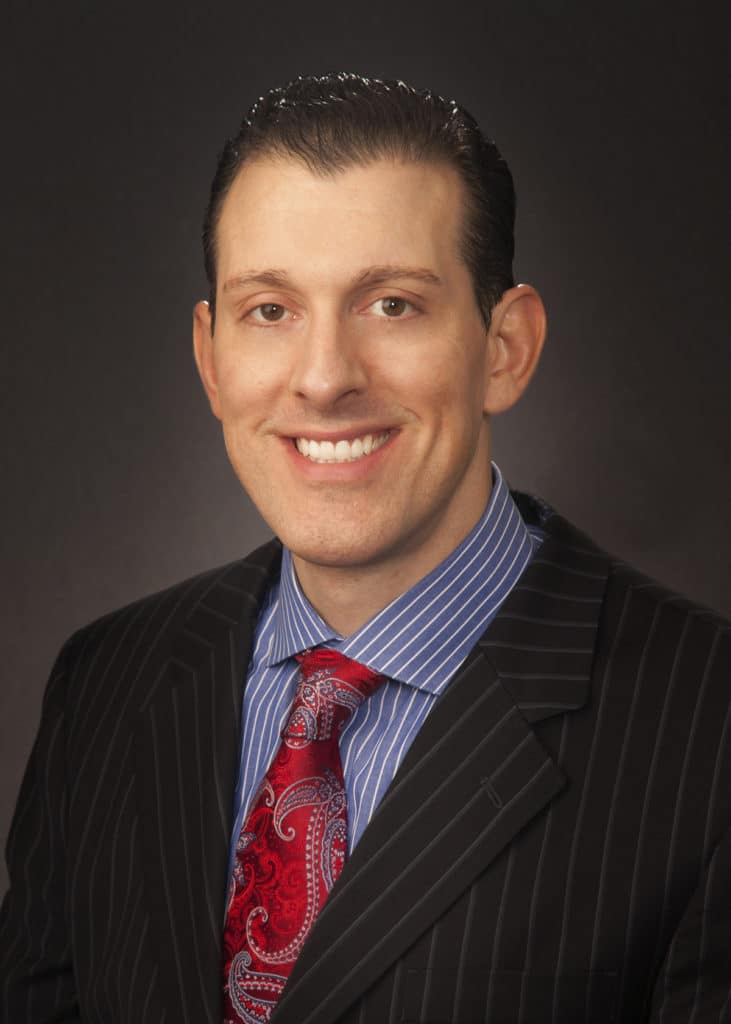 Business headshot on a dark gray backdrop