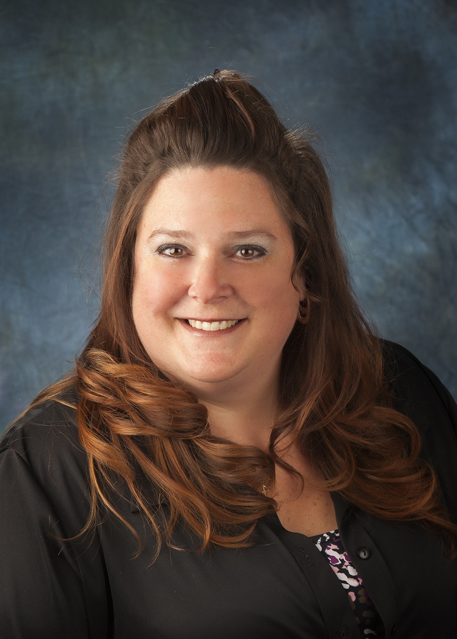 Staff headshot on a blue-gray backdrop for a company website and directory