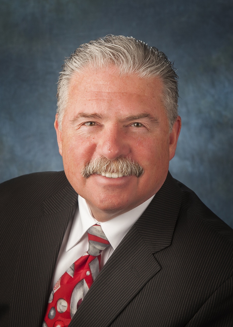Staff headshot on a blue-gray backdrop for a company website and directory