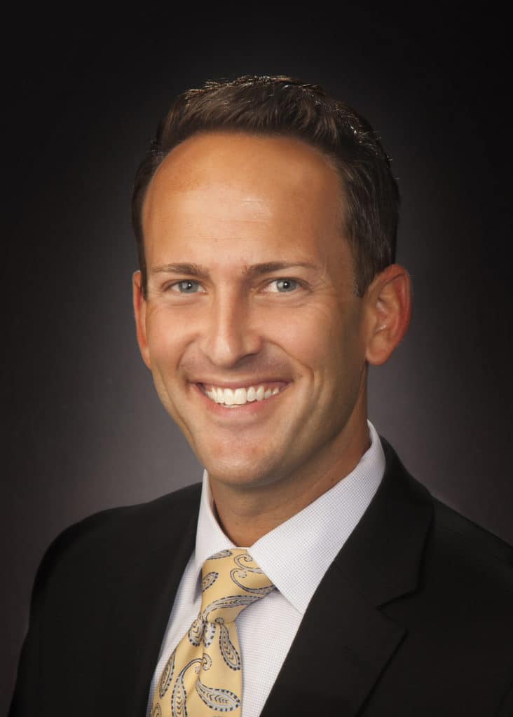 Business headshot on a dark gray backdrop