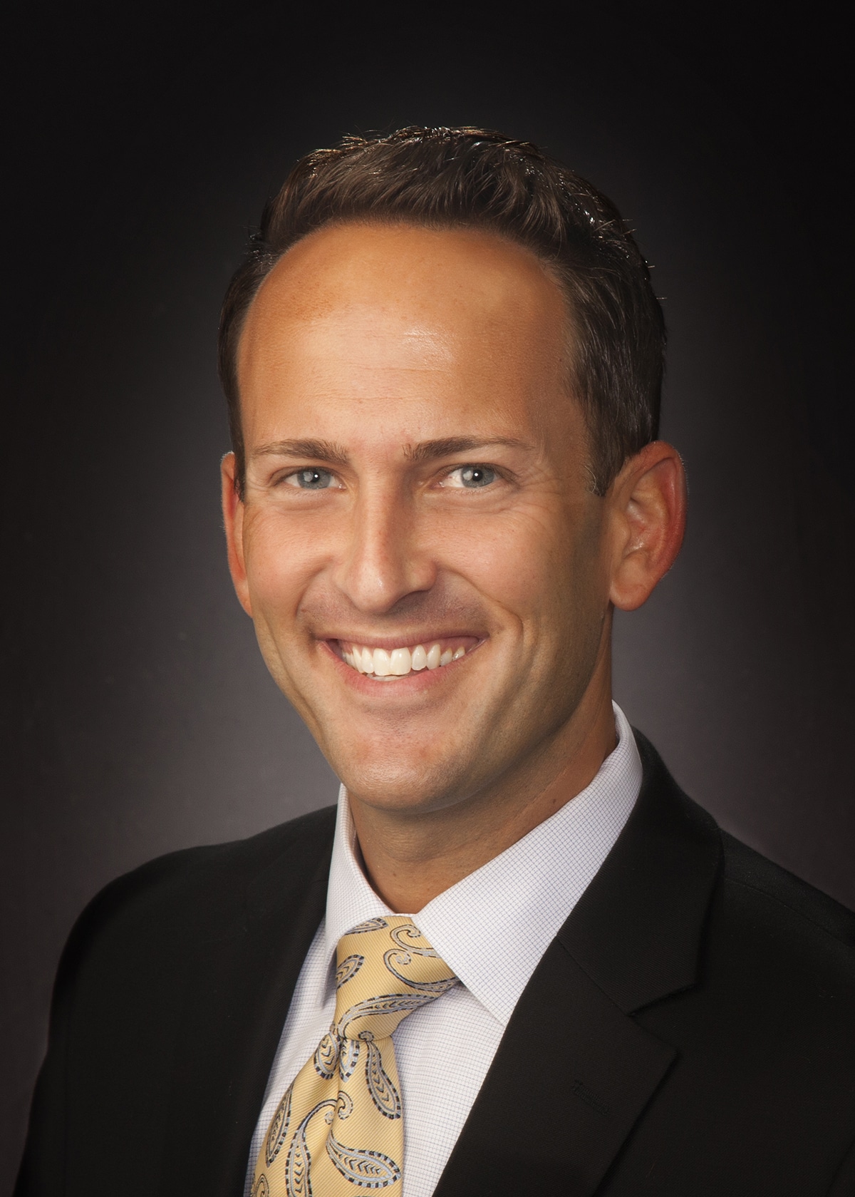 Business headshot on a dark gray backdrop