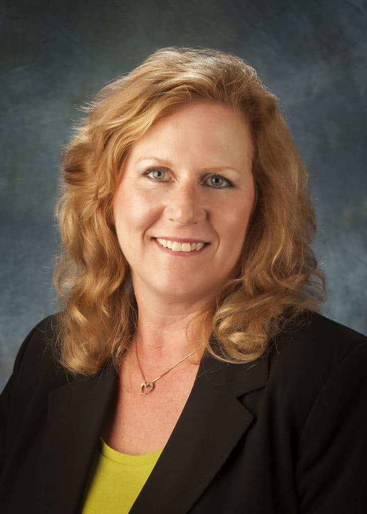 Staff headshot on a blue-gray backdrop for a company website and directory
