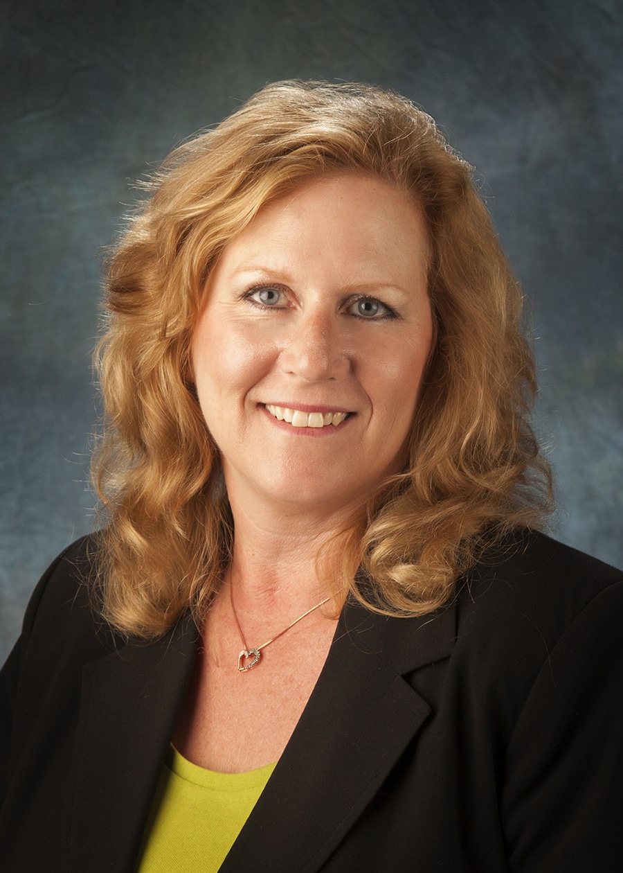Staff headshot on a blue-gray backdrop for a company website and directory