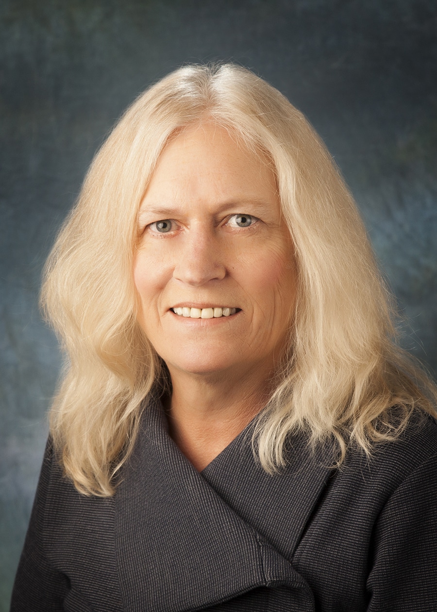 Staff headshot on a blue-gray backdrop for a company website and directory