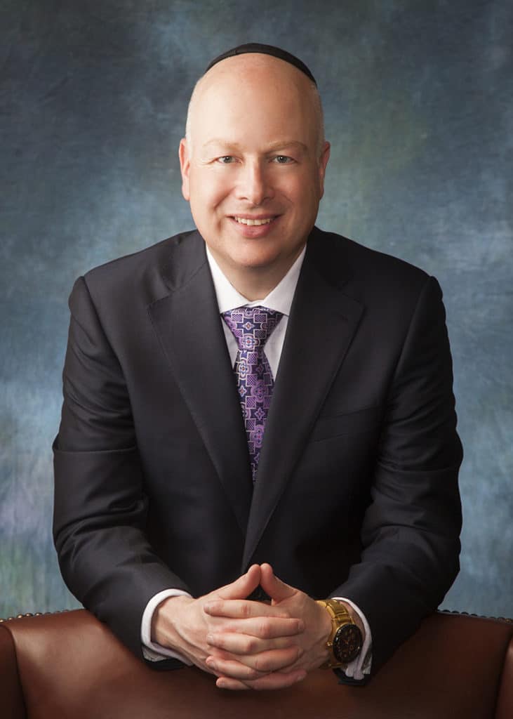 Executive seated portrait on a blue painted backdrop