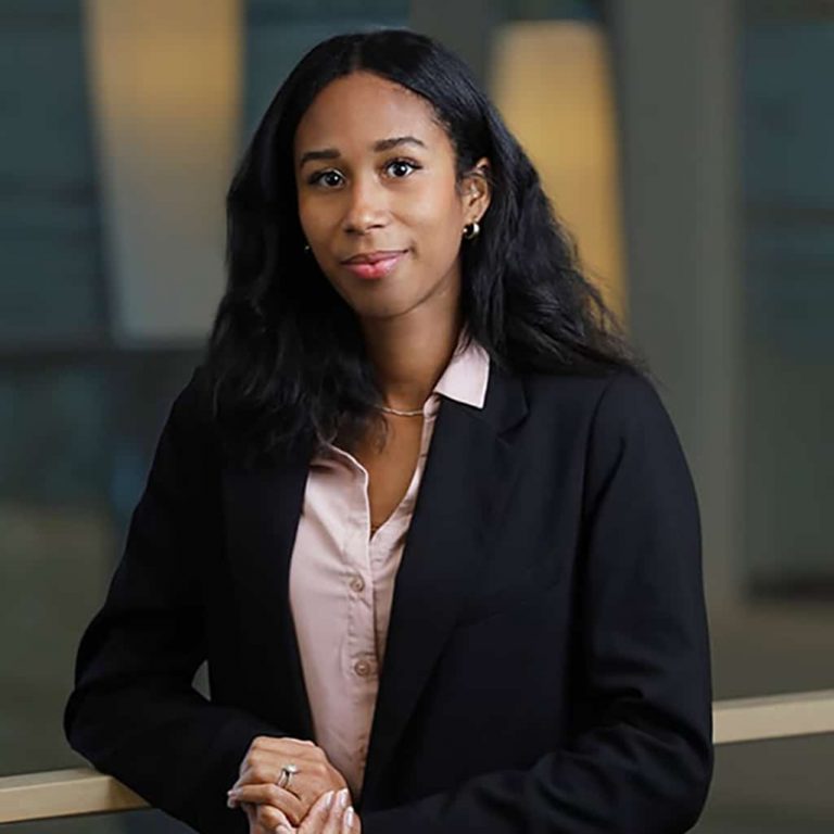 Woman in a black blazer standing in an office with a softly blurred background